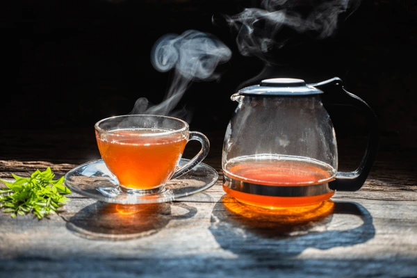 Hot brewed palo azul tea in a clear glass teapot and cup with steam