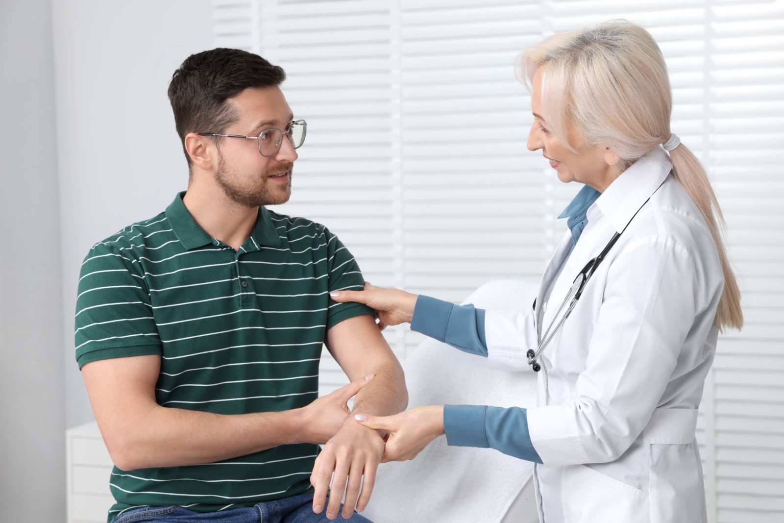 Doctor examining a patient's arm during a clinical consultation to evaluate capillary resistance and fragility